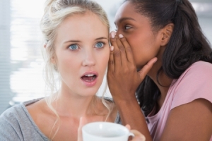 20630232 - young woman whispering secret to her shocked friend at home